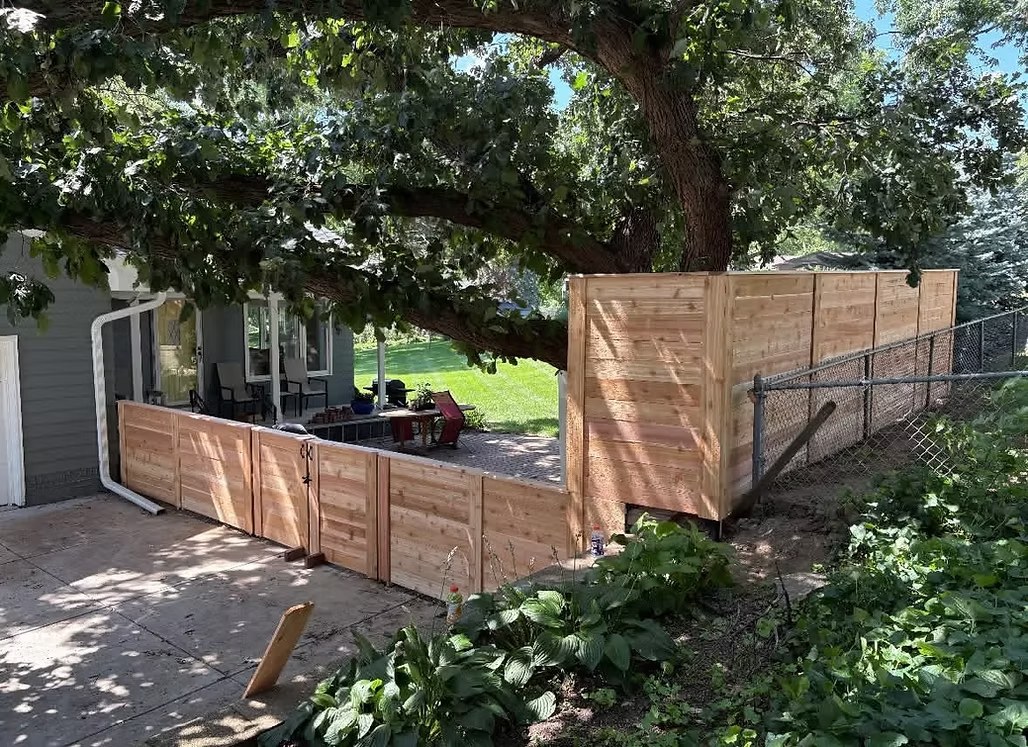 Custom wood privacy fence built around a patio and mature tree in Bellevue, NE
